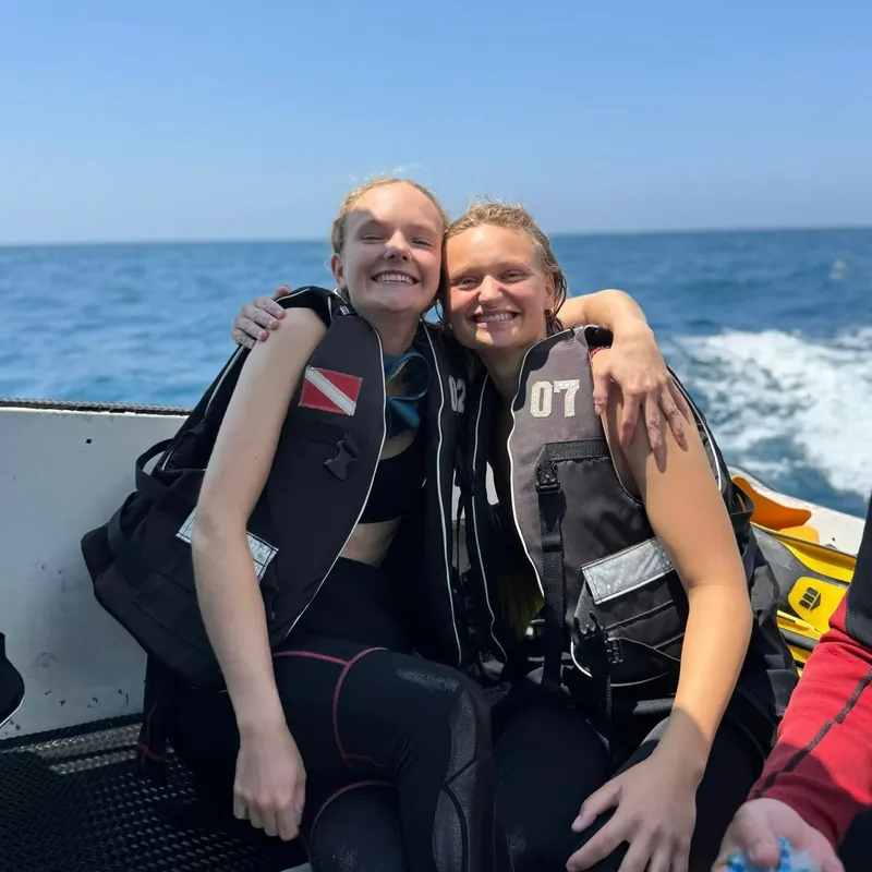 Deux jeunes femmes souriantes en gilets et détendeurs sur un bateau