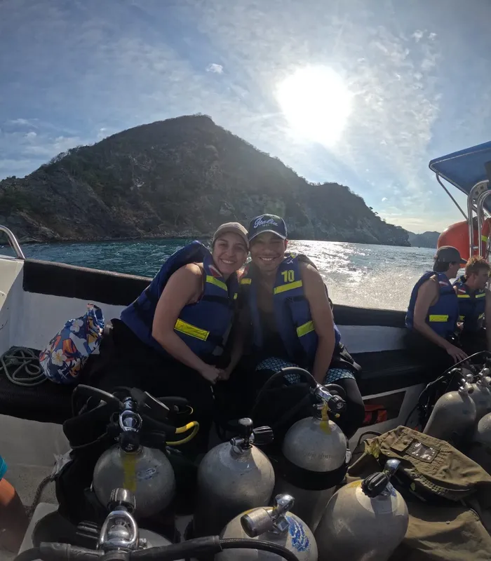 Plongeuses souriantes sur un bateau avec des bouteilles et gilets