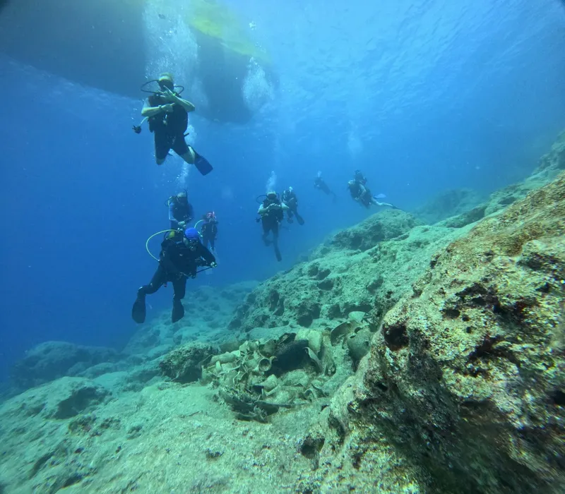 Groupe de plongeurs explorant un fond marin rocheux en bleu