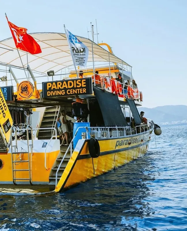 Bateau de plongée jaune et bleu avec des plongeurs à bord en mer