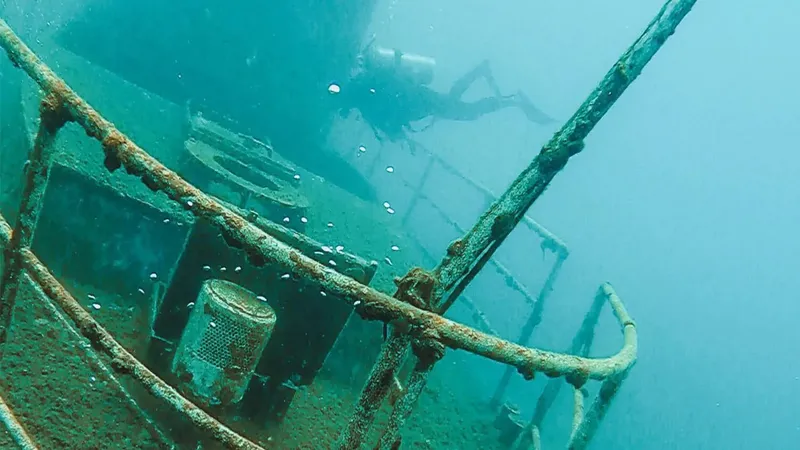 Plongeur explorant l'épave d'un navire rouillé en milieu aquatique
