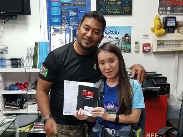 Deux personnes souriantes posent avec un certificat de plongée