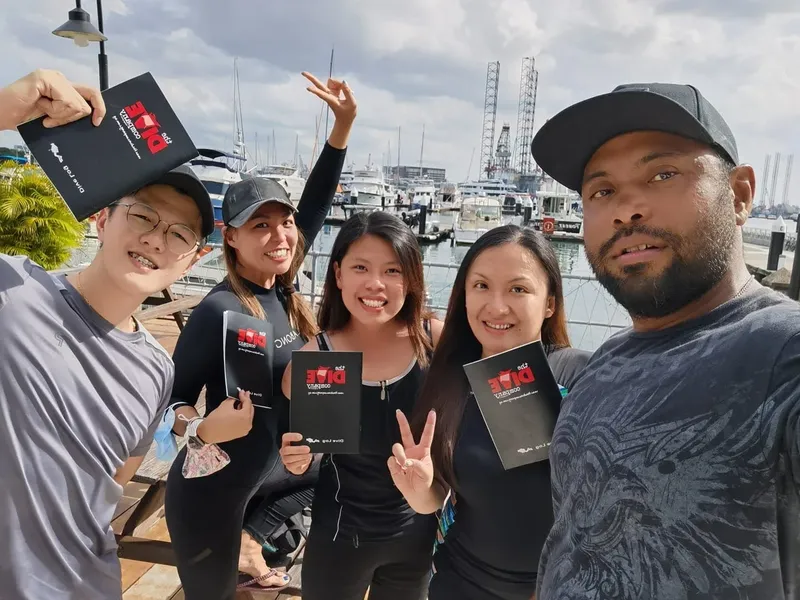 Groupe de plongeurs souriants tenant des cartes de certification en extérieur