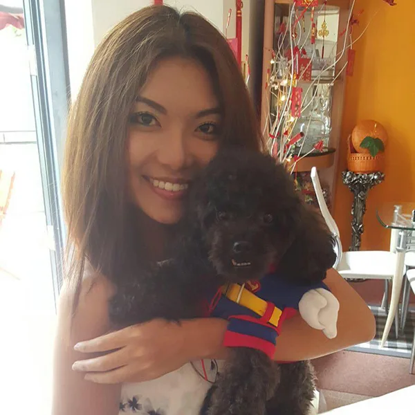Femme souriante tenant un petit chien noir dans un intérieur coloré