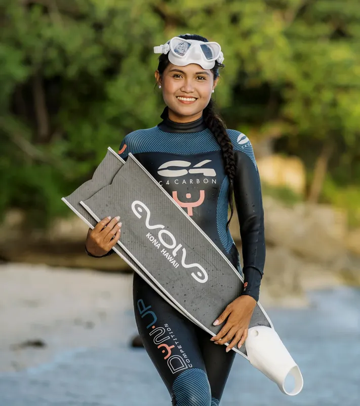 Jeune femme souriante tenant une planche de plongée sur une plage