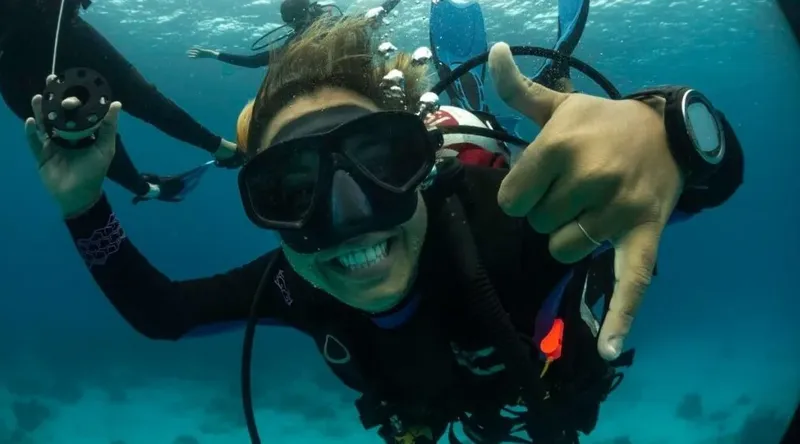 Plongeur souriant faisant un signe de paix sous l'eau