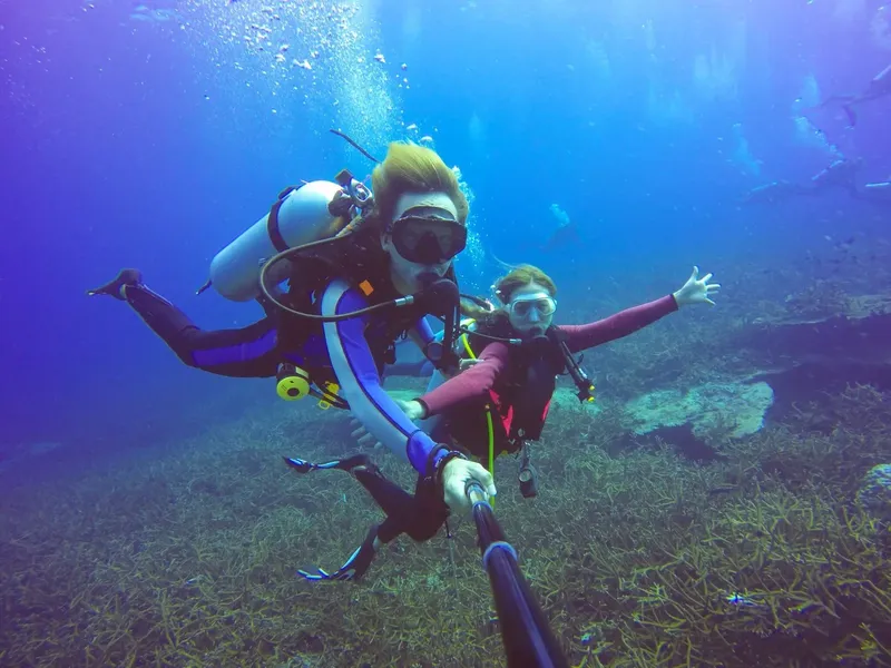Deux plongeurs souriants prennent un selfie sous l'eau en pleine mer