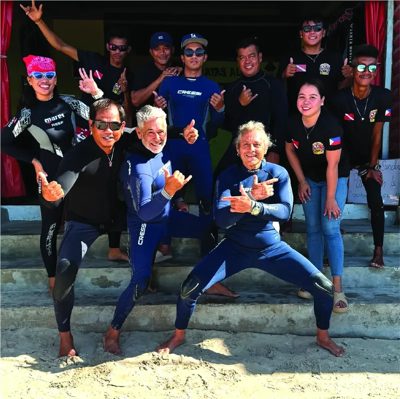 Groupe de plongeurs souriants posant pour une photo en combinaison de plongée