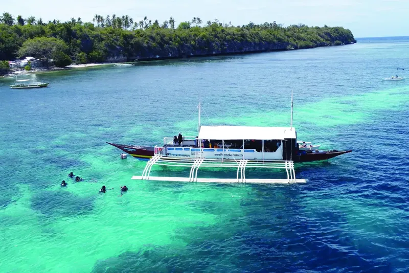 Bateau de plongée avec des plongeurs dans une eau turquoise claire