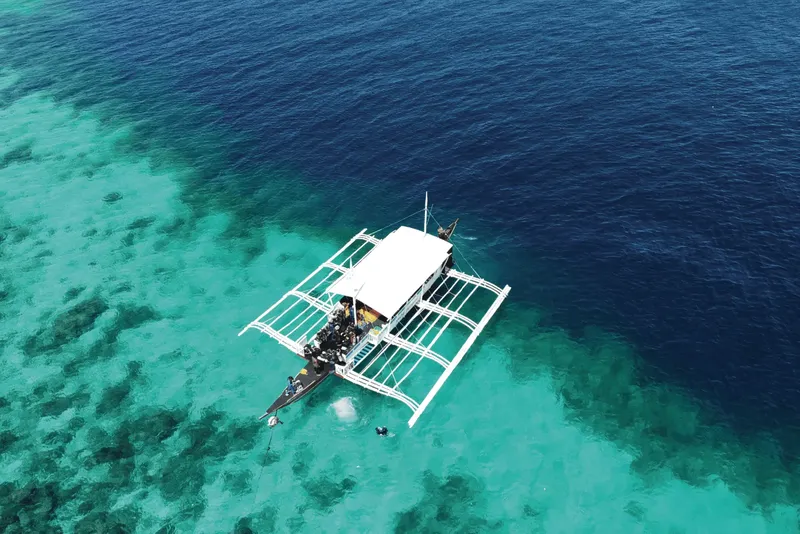 Vue aérienne d'un bateau de plongée avec des plongeurs en mer turquoise