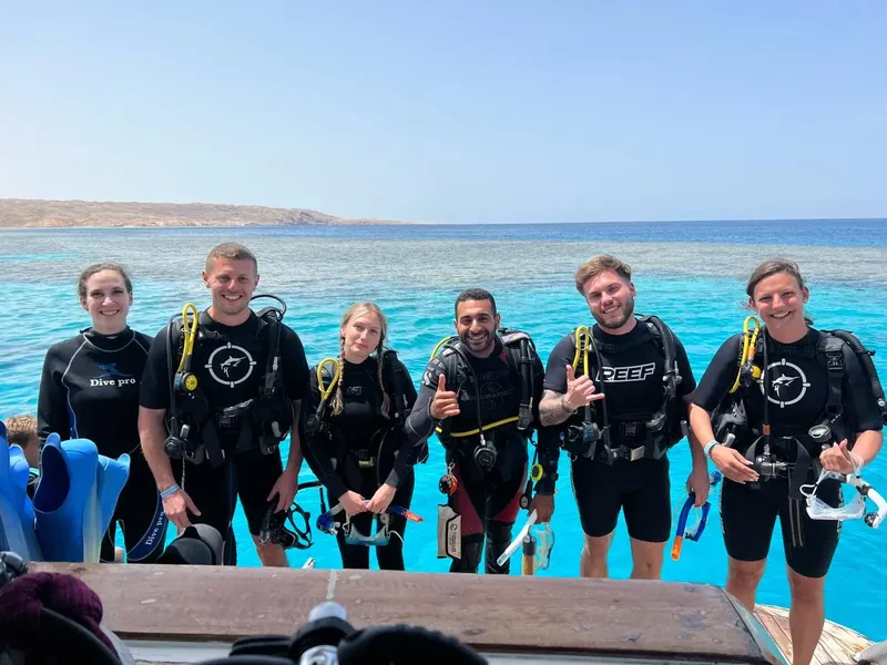 Groupe de plongeurs souriants équipés sur un bateau en mer turquoise