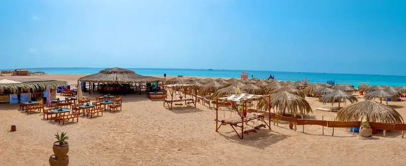Plage de sable avec parasols, tables et chaises, vue sur la mer