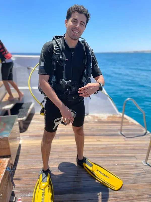 Plongeur souriant debout sur un ponton avec son équipement complet