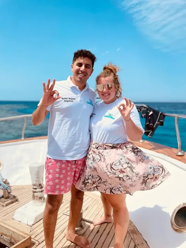Deux personnes souriantes font le signe OK sur un bateau