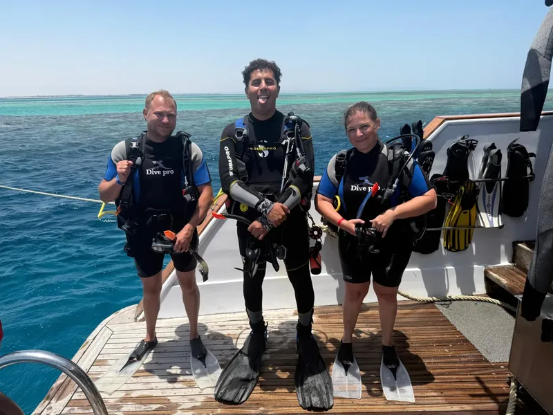 Trois plongeurs souriants sur le pont d'un bateau de plongée