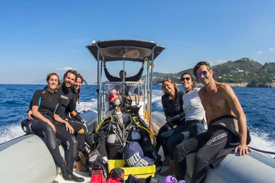 Groupe de plongeurs souriants sur un bateau semi-rigide en mer