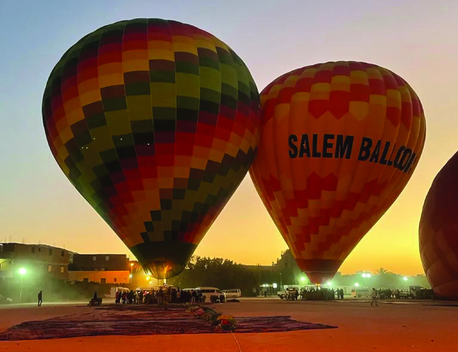 Deux montgolfières colorées s'élèvent au-dessus d'un groupe de personnes