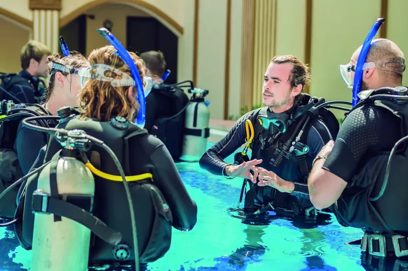 Plongeurs en formation dans une piscine, instructeur expliquant les gestes