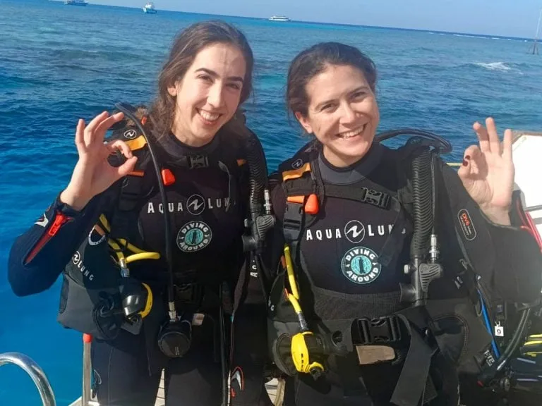 Deux plongeuses souriantes sur un bateau, équipées et prêtes à plonger
