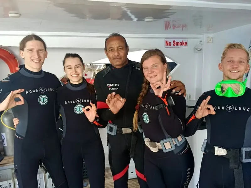 Groupe de plongeurs souriants en combinaison sur un bateau