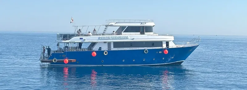 Grand bateau de plongée bleu en mer avec des passagers à bord
