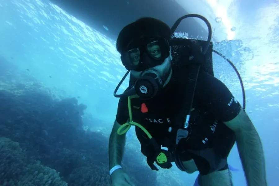 Plongeur en scaphandre noir explore les fonds marins bleus et clairs