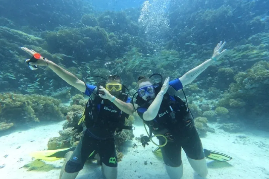 Deux plongeurs souriants avec les bras ouverts dans l'eau