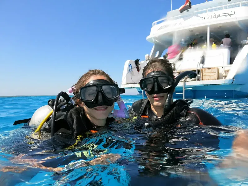 Deux plongeuses souriantes avec masque et gilet en mer