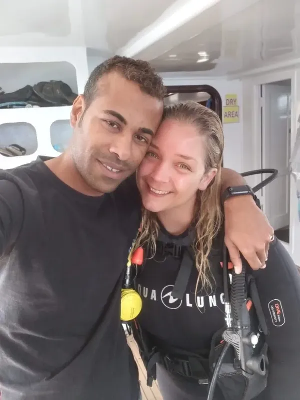 Deux plongeurs souriants posent pour un selfie à bord d'un bateau