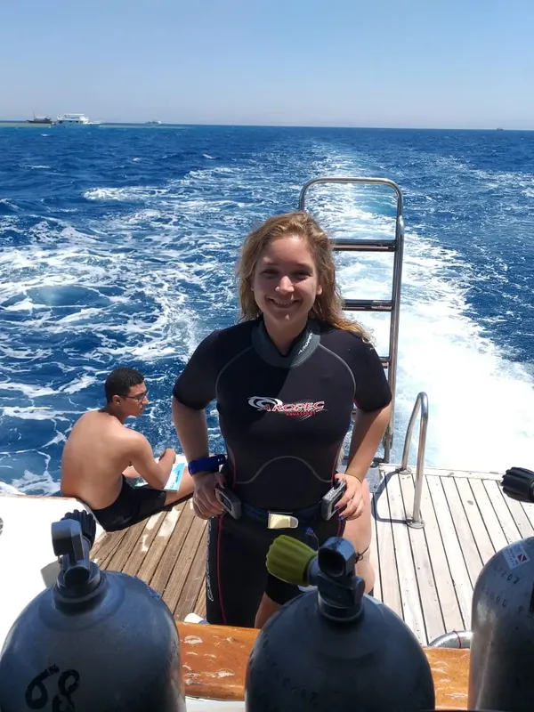 Plongeuse souriante sur le pont d'un bateau avec des bouteilles