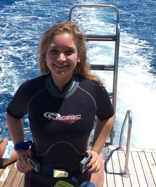 Jeune femme souriante en combinaison de plongée sur un bateau
