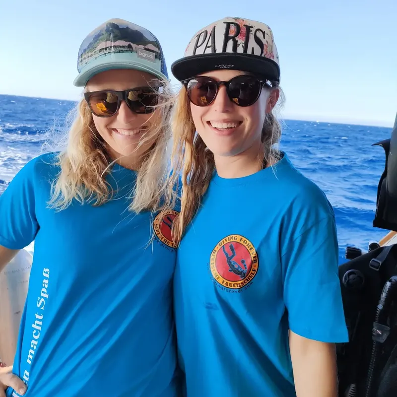Deux plongeuses souriantes sur un bateau en mer, portant des masques