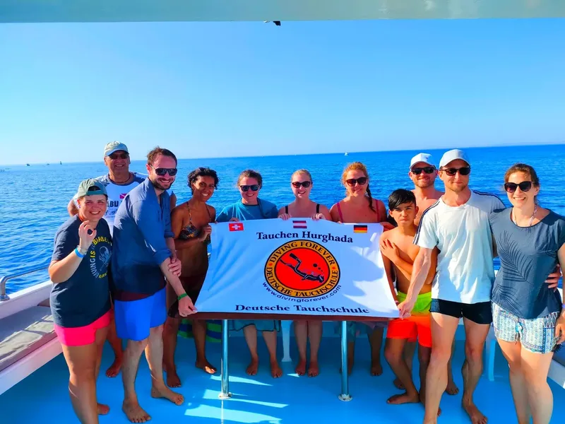Groupe de plongeurs souriants posant avec un drapeau sur un bateau