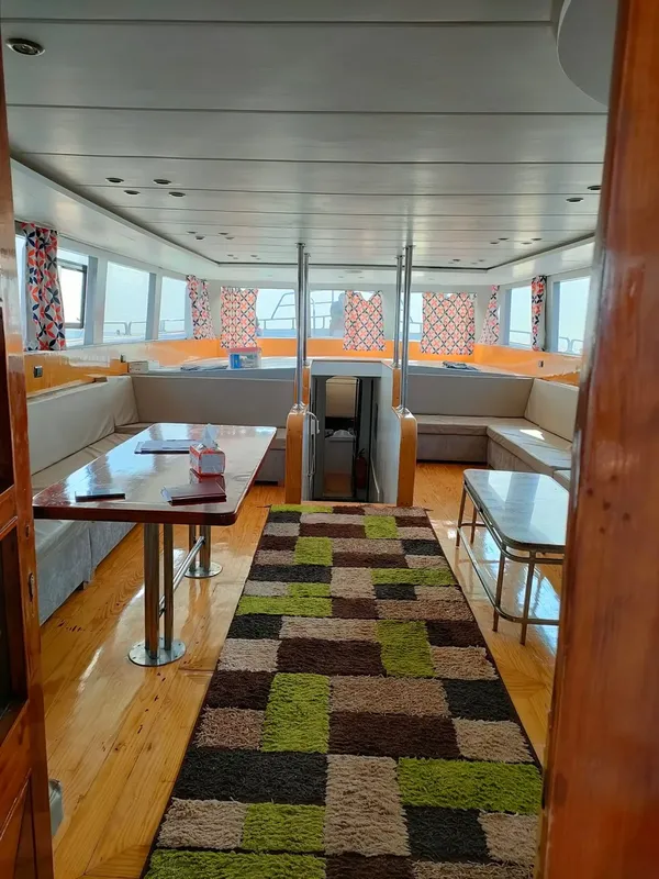 Intérieur d'un bateau de plongée avec tables, banquettes et tapis coloré