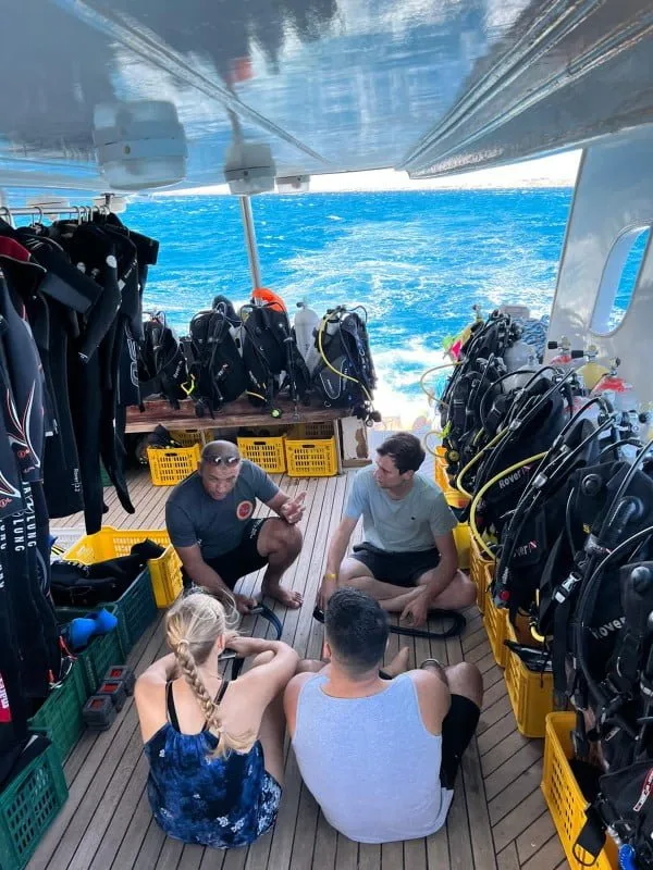 Plongeurs assis sur le pont d'un bateau discutent avec un instructeur