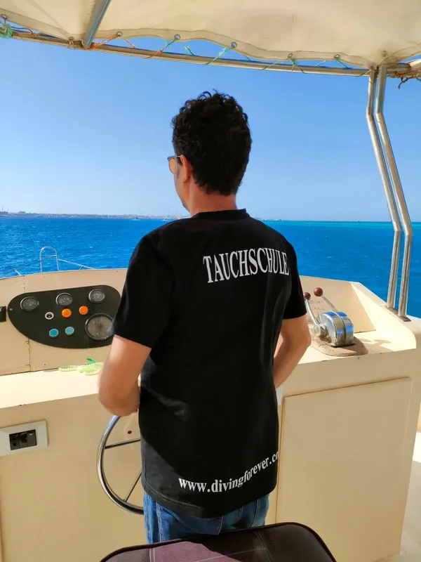 Homme de dos sur un bateau de plongée, vue sur la mer