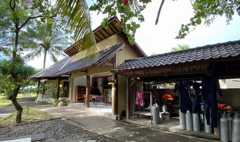Bâtiment avec combi de plongée et bouteilles devant un jardin tropical