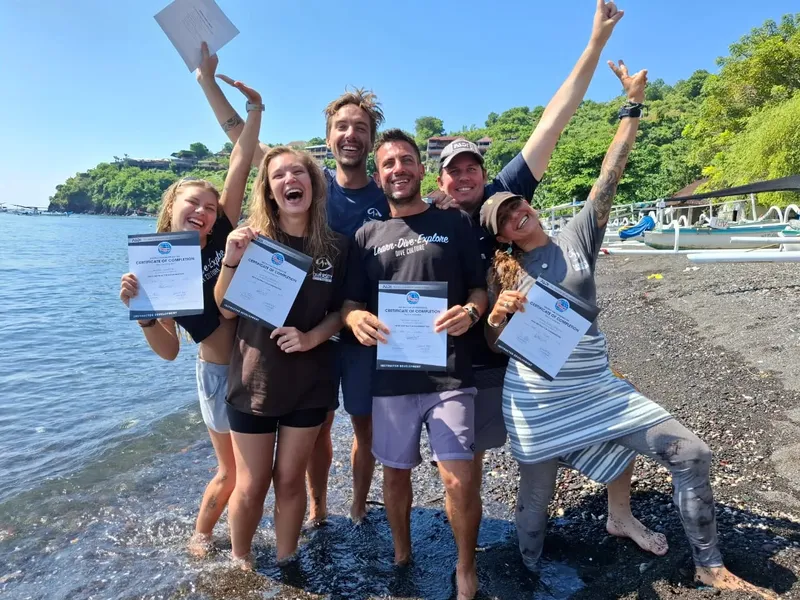 Groupe de plongeurs célébrant avec leurs certificats sur une plage