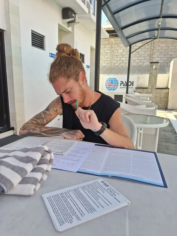 Un homme concentré remplit un formulaire à une table en extérieur