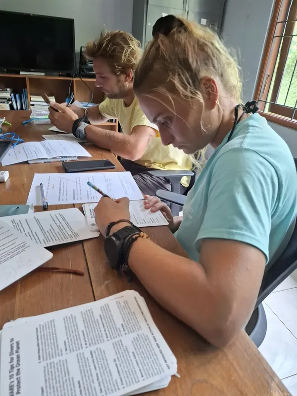 Trois personnes suivent une formation théorique à une table avec des documents