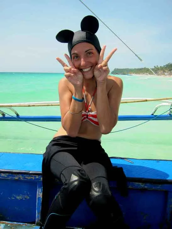 Jeune femme souriante sur un bateau, signe de la victoire