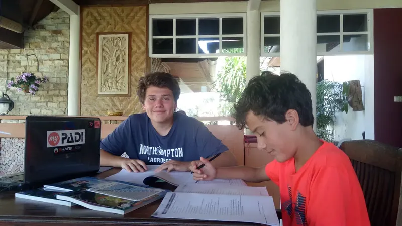 Deux jeunes hommes étudient des documents de plongée devant un ordinateur portable