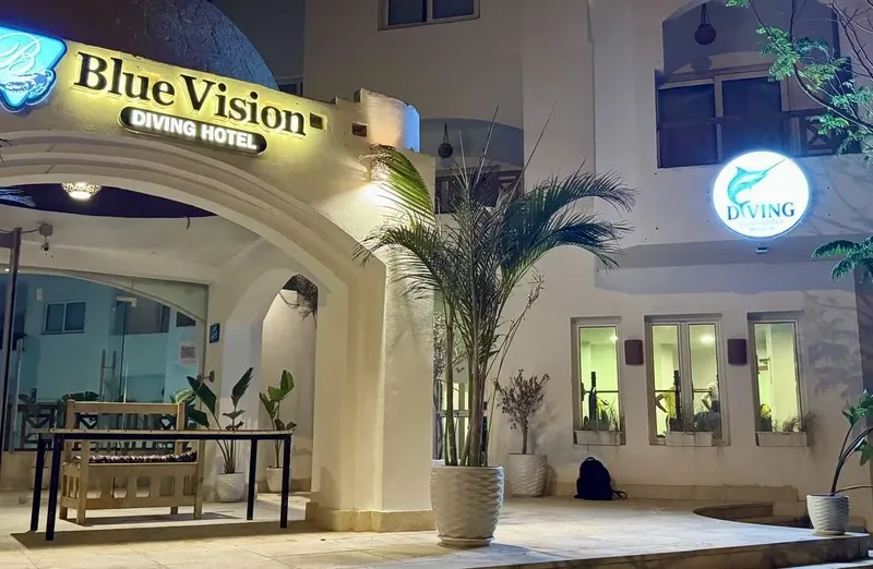 Façade d'un hôtel de plongée avec enseigne lumineuse et palmiers