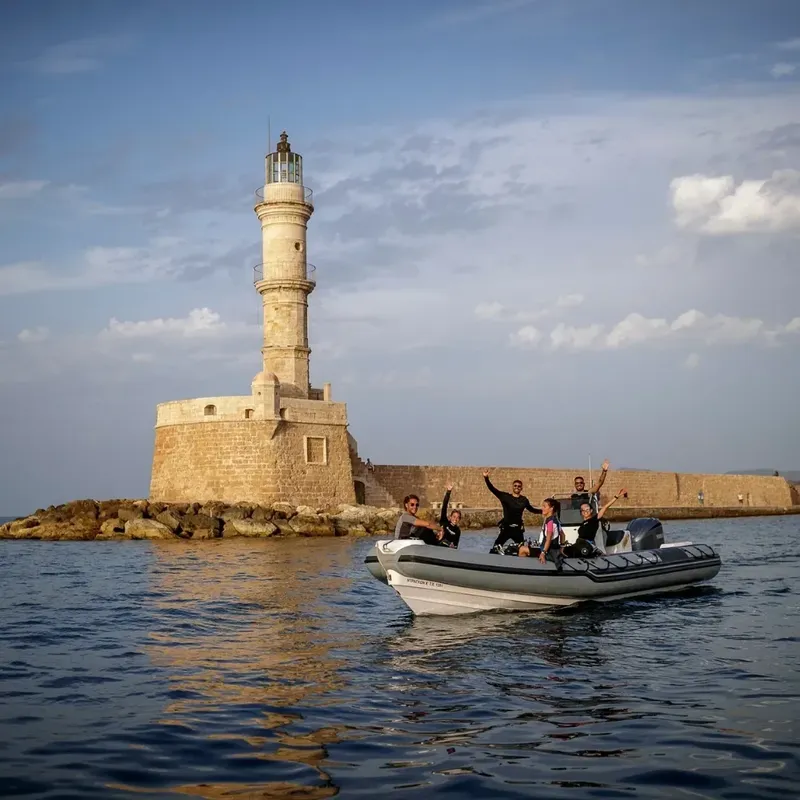 Un groupe de personnes sur un bateau semi-rigide devant un phare