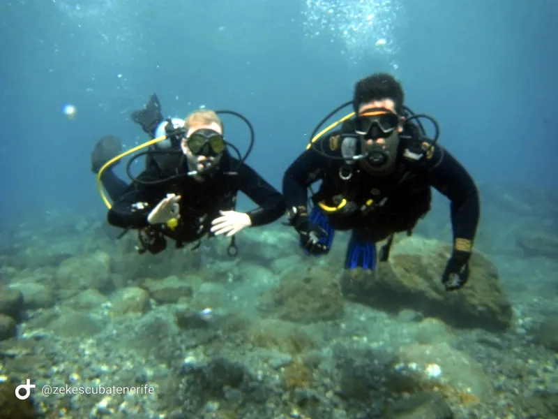Deux plongeurs souriants regardent la caméra au fond de la mer