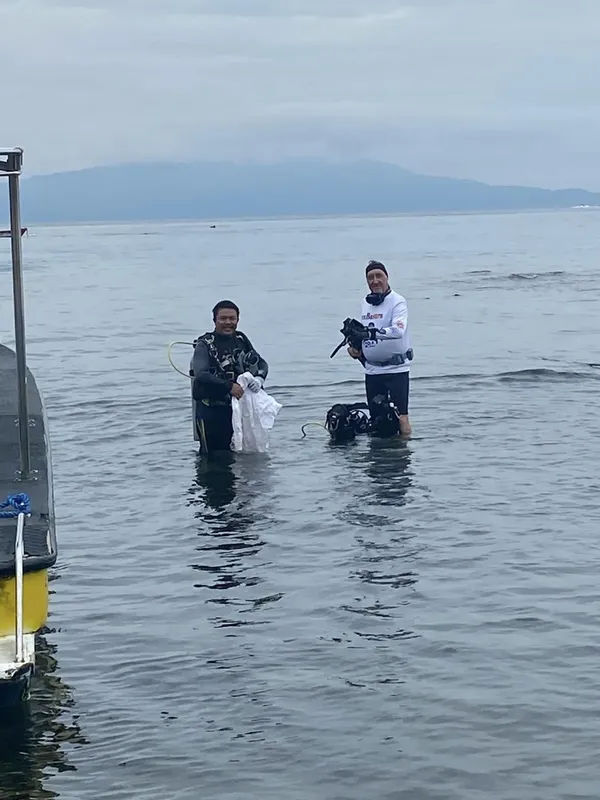 Deux plongeurs en combinaison sortent de l'eau, équipement visible