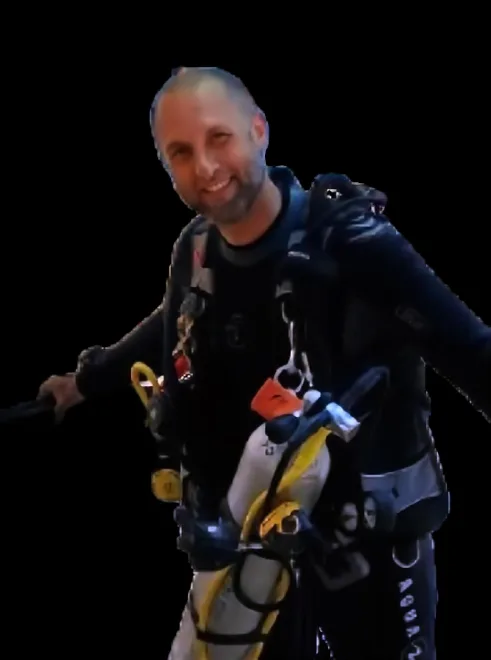 Plongeur souriant équipé de son matériel complet sur fond noir