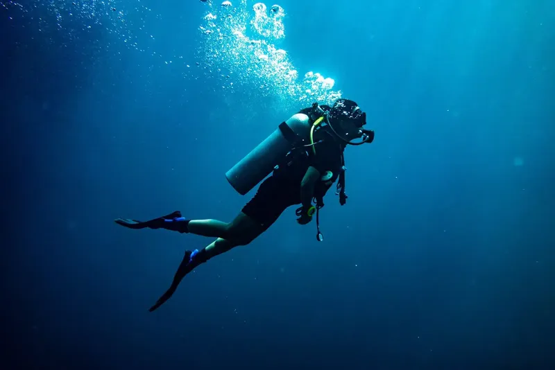 Plongeur en combinaison explore les profondeurs bleues de l'océan