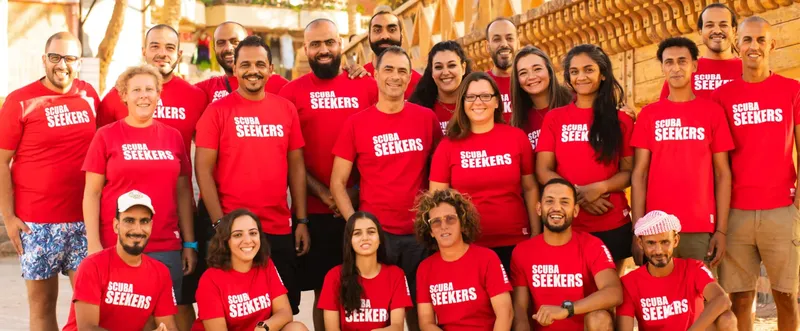 Groupe de personnes souriantes portant des t-shirts rouges devant un mur