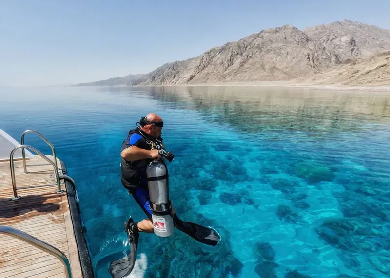 Plongeur s'apprête à entrer dans une mer turquoise et ensoleillée